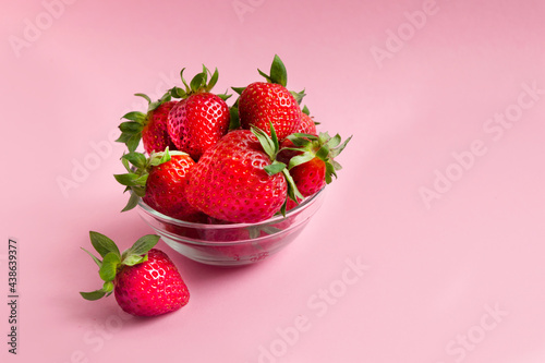 red strawberries in the plate on pink background