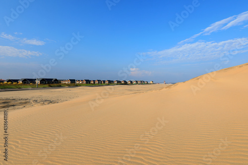 Wooden houses and sand dunes against a blue sky background