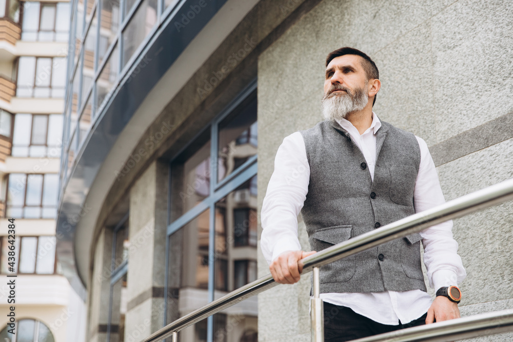 Portrait of a gray bearded and brutal man spending time on the clean urban spaces.