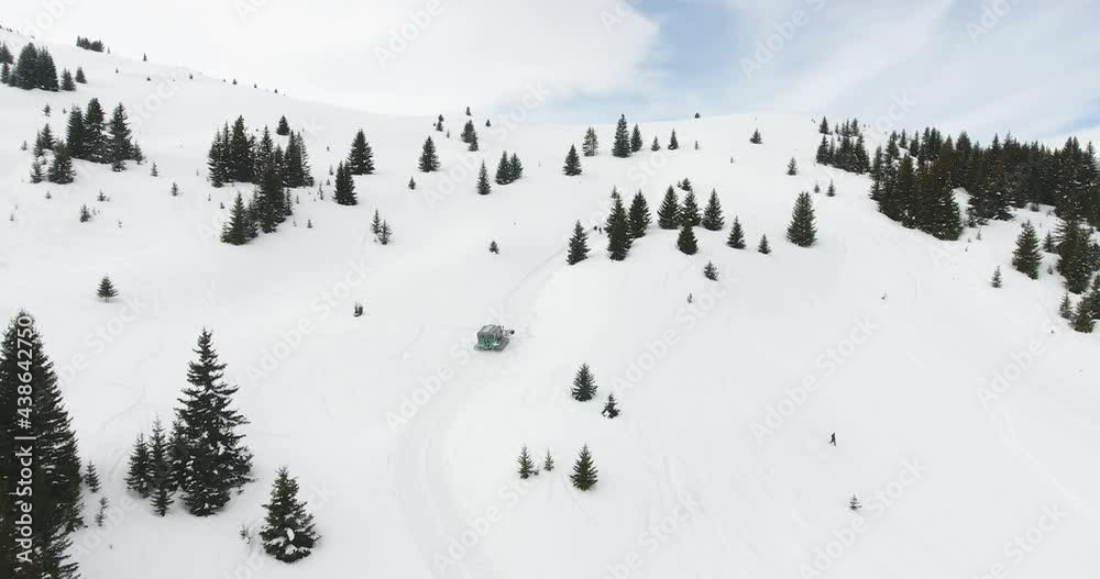 Snowcat ratrack driving on the off piste ski slope up the snow covered mountain peak, accident and emergency situation for hurted skier. Aerial view Snowcat ratrack driving on the off piste ski slope up the snow covered mountain peak, accident and emergency situation for hurted skier. Aerial view