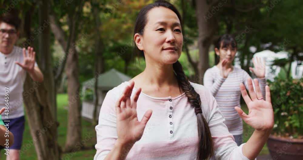 Happy asian parents exercising in garden with son and daughter, practicing tai chi together