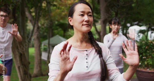 Happy asian parents exercising in garden with son and daughter, practicing tai chi together photo