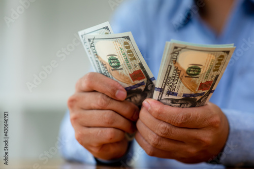 Business man hands counting US Dollar bills or paying in cash .