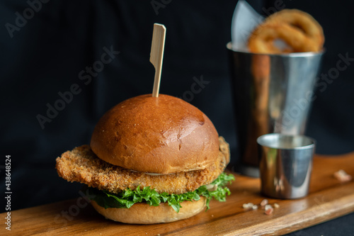 Sea bass Fish Burger with french fries aioli lettuce pickled fried onion ring on  wooden board