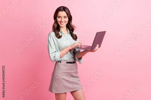 Photo of charming pretty cheerful young woman hold hands laptop smile blogger isolated on pink color background