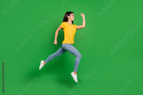 Full size profile side photo of charming pretty young woman jump up run empty space isolated on green color background