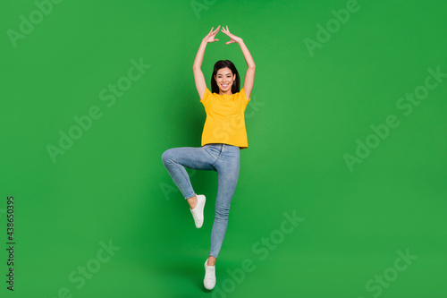Full length photo of cheerful active young woman jump up air ballet dance isolated on green color background