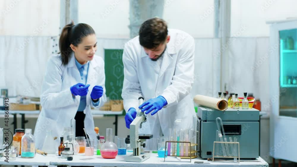 Scientist man and woman looking through the microscope with his colleague discussing together in the chemistry laboratory concept of science testing laboratory industry Scientist man and woman looking through the microscope with his colleague discussing together in the chemistry laboratory concept of science testing laboratory industry