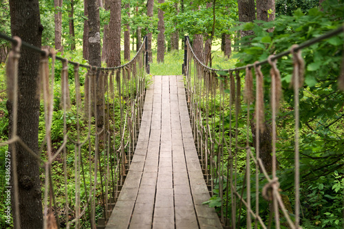 Suspension wooden bridge in the forest. Rope bridge suspended between two hills in the woods