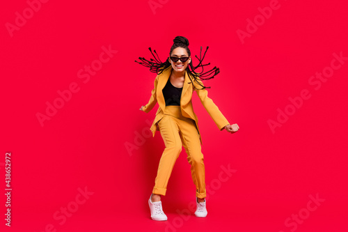 Full body photo of cool lady dance wear eyewear yellow suit isolated on vivid red color background © deagreez