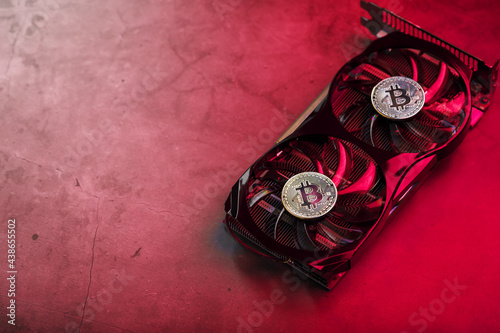 On the fans of a powerful video card, the coins of the Bitcoin cryptocurrency with a red backlight are displayed.