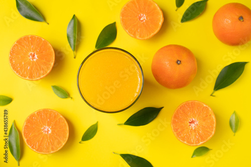 Glass of orange juice on yellow background.