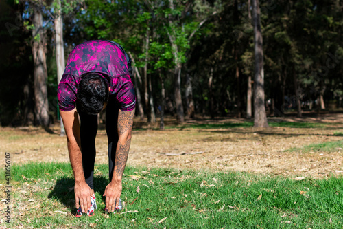 Attractive young Latino man in shape stretching before exercising