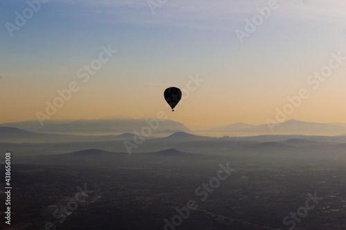 Globo aerostático volando en el cielo sobre montañas