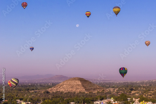 Globos aerostáticos volando cerca del templo del sol de Teotihuacan en México, amanecer con la luna, azul colorido