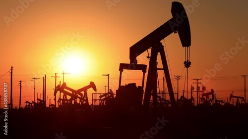The sun rises behind oil pumps in California