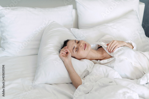 Young woman sleeping on white bedclothes in bedroom
