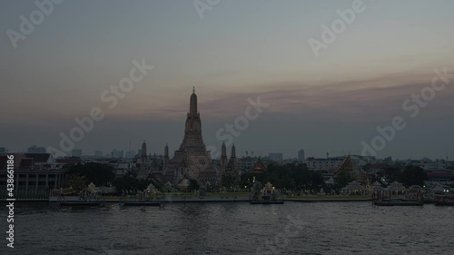 Sunset time lapse of Wat Arun temple and boat traffic at Chao Phraya river at Bangkok, Thailand. photo