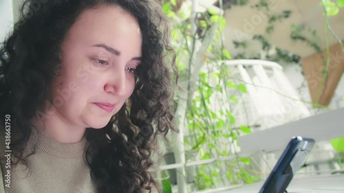 Sad woman reading mobile phone content sitting on a couch at home