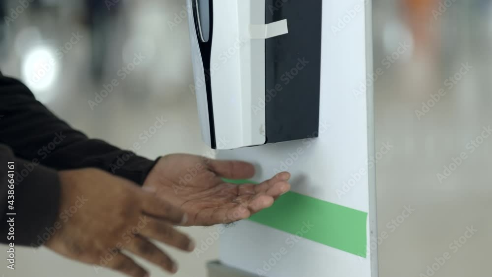 Close up hand man taking automatic spray alcohol hand washing at airport terminal. Traveling during the epidemic keep clean and hygiene.