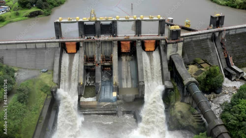 Aerial front view, zooming out on a large hydroelectric dam in South America with the gates open to let the water through Aerial front view, zooming out on a large hydroelectric dam in South America with the gates open to let the water through