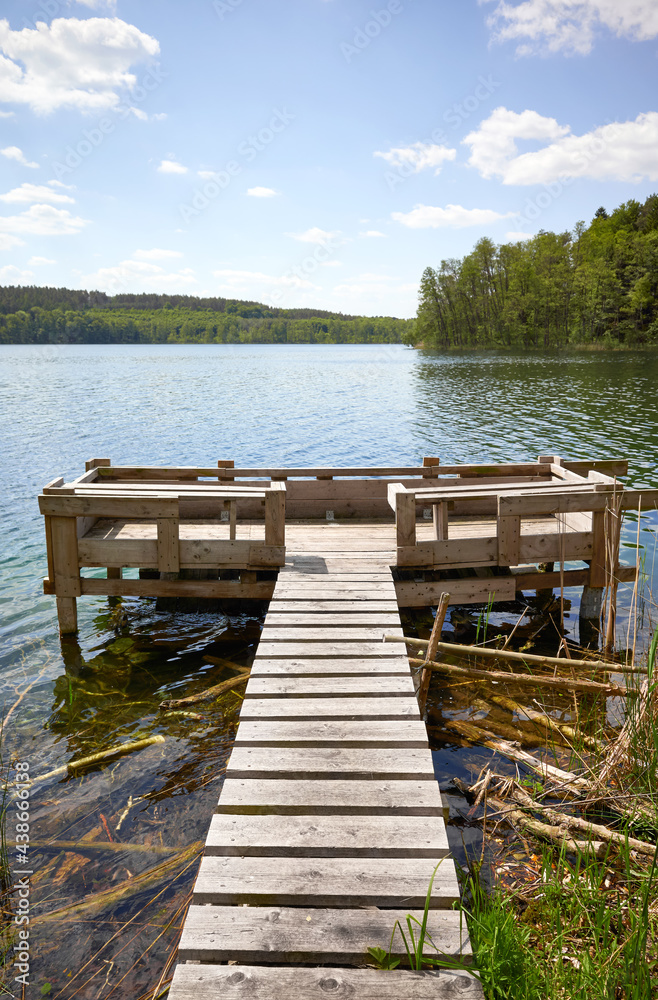 Naklejka premium Wooden fishing platform at Slowa Lake on a sunny day, Poland.