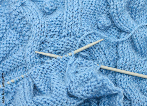 Fotografie Blue knitted fabric and knitting needles