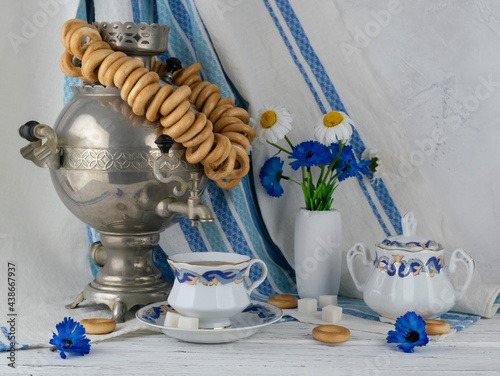 A samovar with driers and tea in a ceramic cup on a light wooden table photo