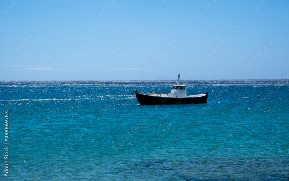 Greece, Cyclades. Traditional boat anchored on blue color sea water