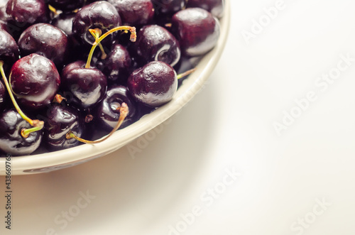 Closeup on fresh and ripe sweet cherries on a white ceramic plate photo