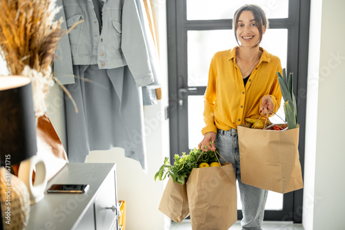 Foto Woman comes home with bags full of fresh groceries, shopping healthy food in eco-packaging