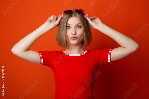 portrait of a beautiful young woman in sunglasses on a red background 