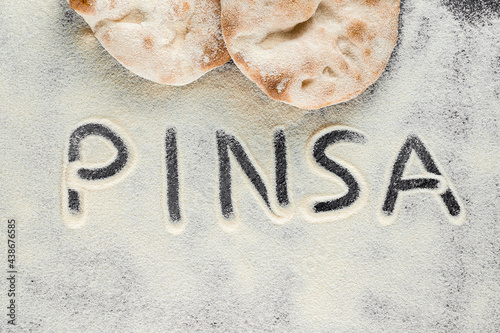 Dough and flour with text pinsa on black background. Pinsa romana and scrocchiarella gourmet italian cuisine. Traditional dish in italy. photo