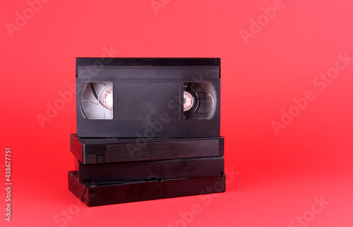 Black videotapes on a red background. Old technologies for video storage photo