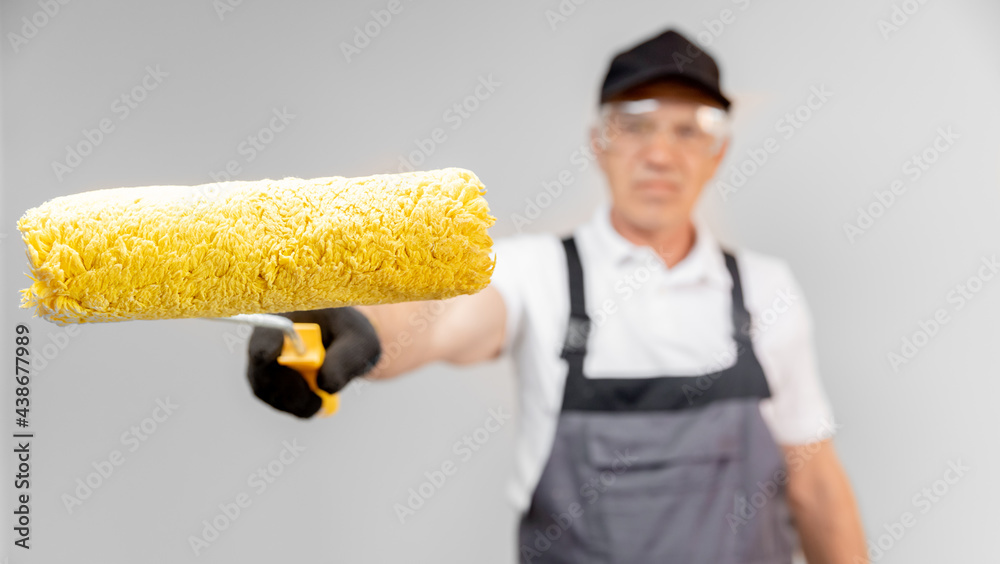 Man builder painter in gloves and uniform holding painting roller repair apartment home Man builder painter in gloves and uniform holding painting roller repair apartment home