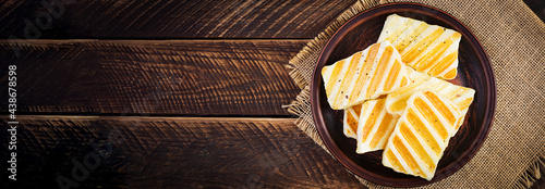 Traditional grilled halloumi cheese on plate on wooden background. Top view, above photo