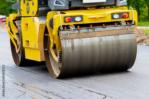 Asphalt paver on the road during asphalt compaction close up. Road repair. Laying a new road