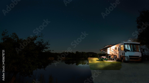 Camping in a motorhome a long side the waters edge at night under a starry sky
