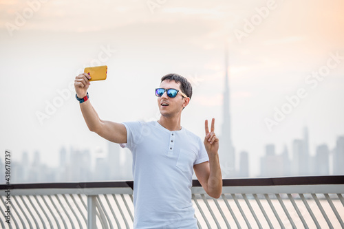 Photography A male traveler takes a selfie on his smartphone against the backdrop of the sky