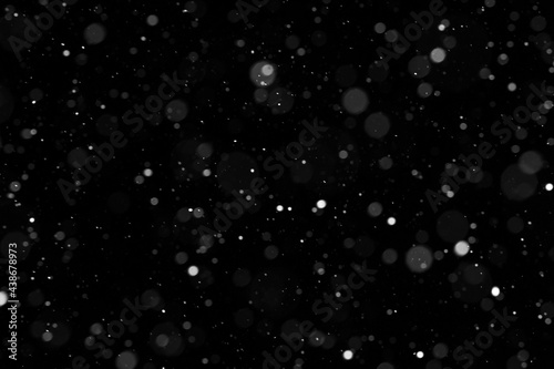 Bokeh of white snow on a black background. Falling snowflakes on night sky background, isolated for post production and overlay in graphic editor.