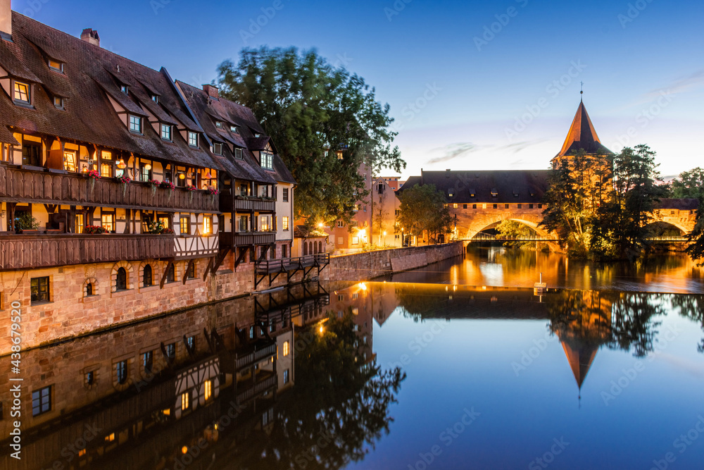 A colourful and picturesque view of the half-timbered old houses on the banks of the Pegnitz river in Nuremberg, Franconia, Germany illuminated at night