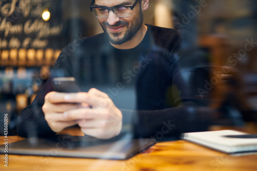 Positive ethnic man browsing cellphone