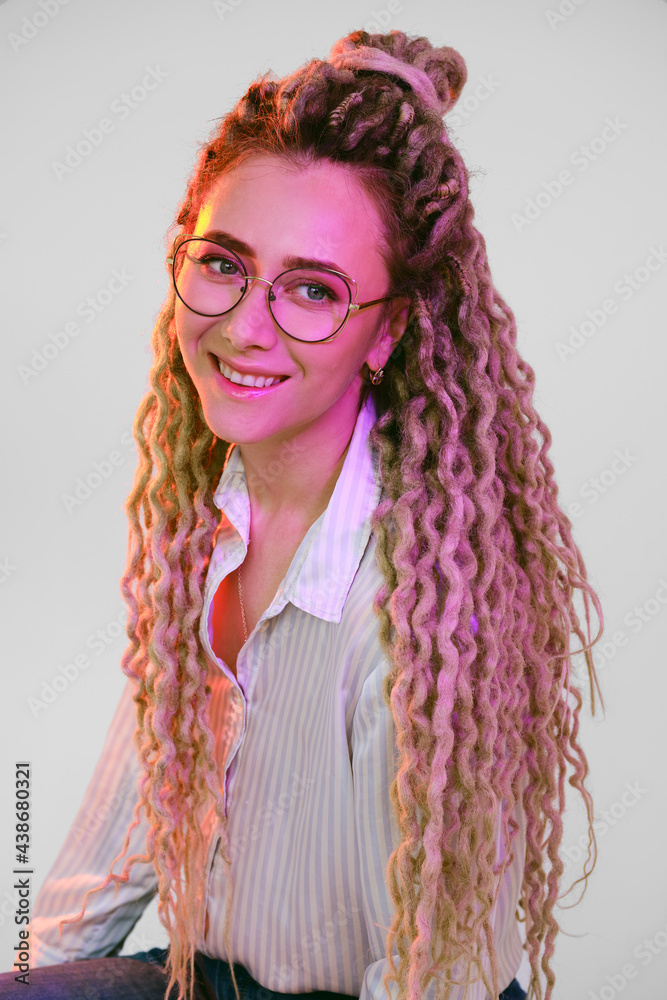 Woman in glasses with dreadlocks under color lights Woman in glasses with dreadlocks under color lights