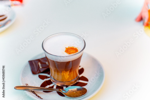 cortado de café con leche natural con azucarillo y cucharita en mesa de bar
 photo