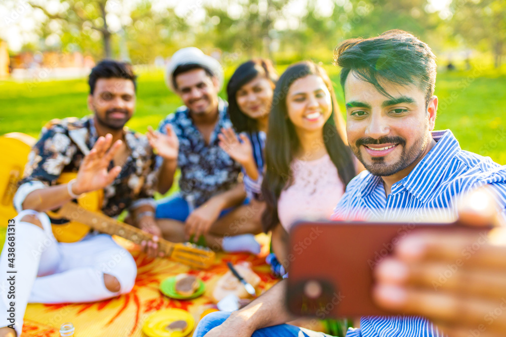 indian students having a lunch and taking selfie on camera phone in Delhi park outdoors indian students having a lunch and taking selfie on camera phone in Delhi park outdoors