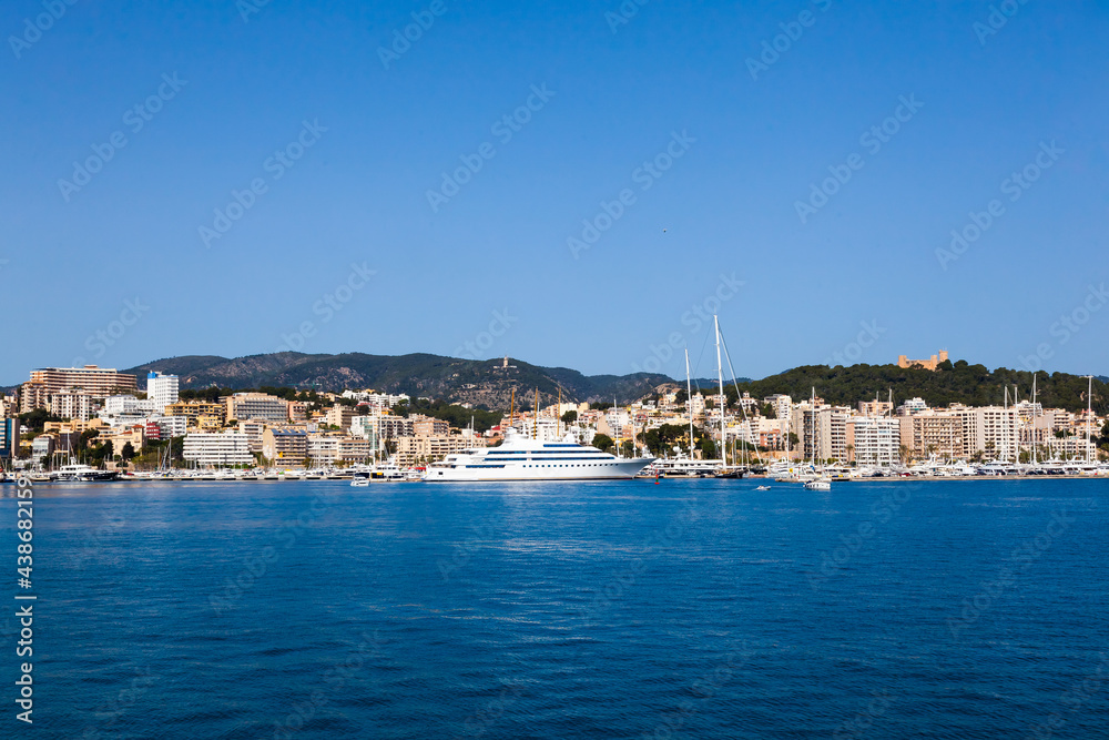 View of the bay of Palma de Mallorca with luxury yachts, buildings, mountains and beautiful clouds.