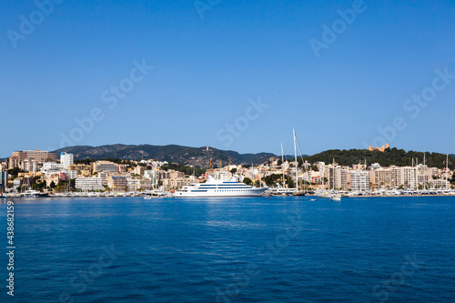 View of the bay of Palma de Mallorca with luxury yachts, buildings, mountains and beautiful clouds.