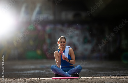 Fototapeta Naklejka Na Ścianę i Meble -  Active young woman resting after exercise hydrating with milkshake.