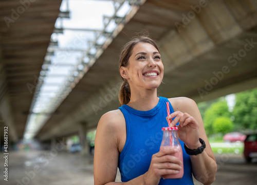Bild auf Leinwand Portrait of fit woman smiling laughing holding milkshake outdoors in parking lot