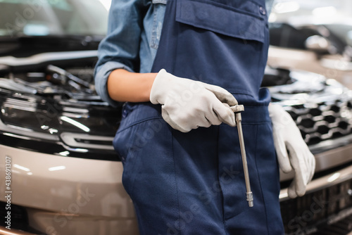 partial view of young african american mechanic holding wrench and standing near car in auto repair service